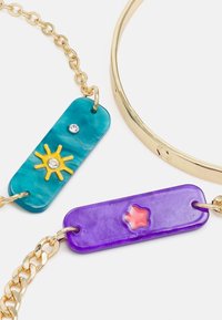 Pulseira colorida com uma corrente dourada e três pendentes retangulares: em teal com um desenho de sol, em roxo com uma forma de estrela e um detalhe brilhante.