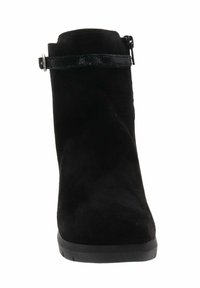 Bottine en daim noir avec une semelle basse, une sangle décorative avec boucle autour du haut et une fermeture éclair sur le côté.