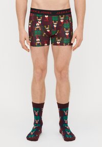 Boxers avec un motif de renne festif sur un fond de tartan bordeaux et vert ; tissu doux ; assortis à des chaussettes coordonnées.