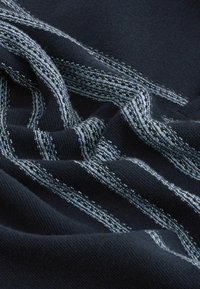 Strickstoff in dunkelmarineblau mit hellblauen vertikalen Streifen. Weiche Textur mit dichter Webart. Die Streifen zeigen kontrastierende Fadenmuster.