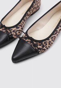 Bailarinas de punta afilada con una puntera de cuero negro y un cuerpo de textil con estampado de leopardo, que cuentan con cordones negros y un suave forro interior.