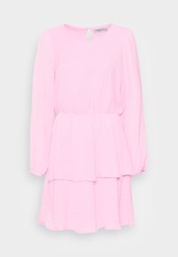 Vestido rosa claro com mangas longas, cintura franzida e saia em camadas. Apresenta um decote redondo e um pequeno detalhe em forma de chave nas costas. Padrão de bolinhas.