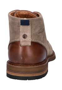 Bruine leren en beige suède enkellaars met gelaagde zool en achterste treklip met knoopdetail.