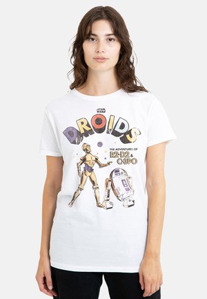 Woman wearing white Star Wars t-shirt with colorful "Droids" text and illustrations of robots C-3PO and R2-D2 on the front.