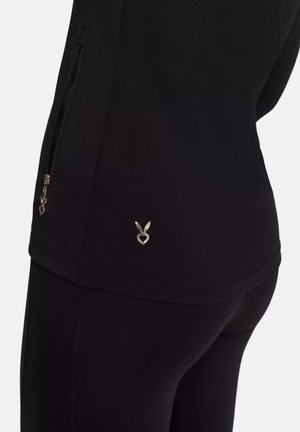 Black athletic top made of smooth fabric, featuring a side zip pocket and a small metallic logo accent near the hem.