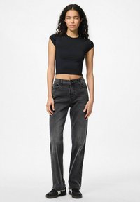Black cropped T-shirt and high-waisted gray jeans with a straight cut. Black sneakers, simple design, smooth texture, overall minimal style.