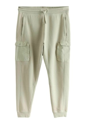 Close-up of a person wearing light green cargo sweatpants with drawstring waist, side pockets, and flap pocket on the thigh, hand in pocket.