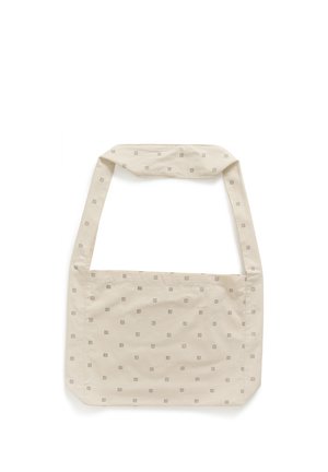 Sac à bandoulière en tissu beige avec de petits motifs carrés marron clair répartis uniformément sur toute la surface et une large sangle.