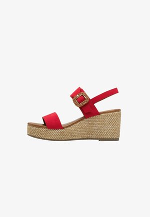 Sandalia de cuña de ante rojo con una plataforma de cuerda texturizada, una tira ancha sobre los dedos y una correa para el tobillo ajustable con un hebilla trenzada.