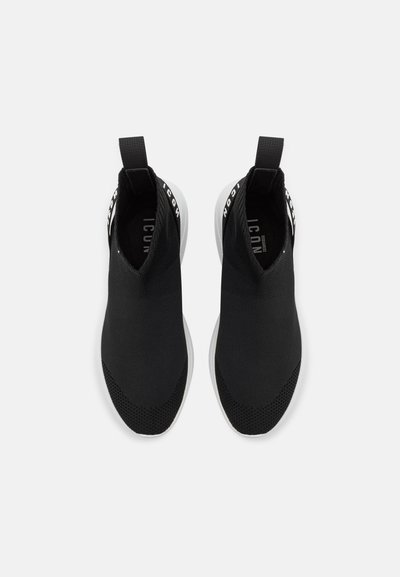 Crne slip-on tenisice s tekstilnim gornjim dijelom, teksturiranim pletenim detaljima i bijelim potplatom. Imaju uvučenu petu i natpis brenda.
