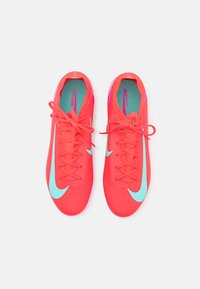 Pantofi de fotbal Nike Mercurial în roz vibrant cu un finisaj texturat, având accente de albastru deschis și șireturi plate, văzuți dintr-o parte.
