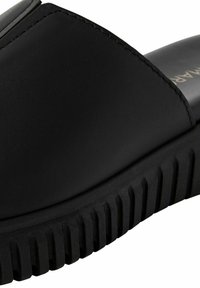 Sandalo nero con tomaia in pelle liscia, design a fasce larghe e suola in gomma rigata per una migliore aderenza. Cuciture sottili decorano i bordi.