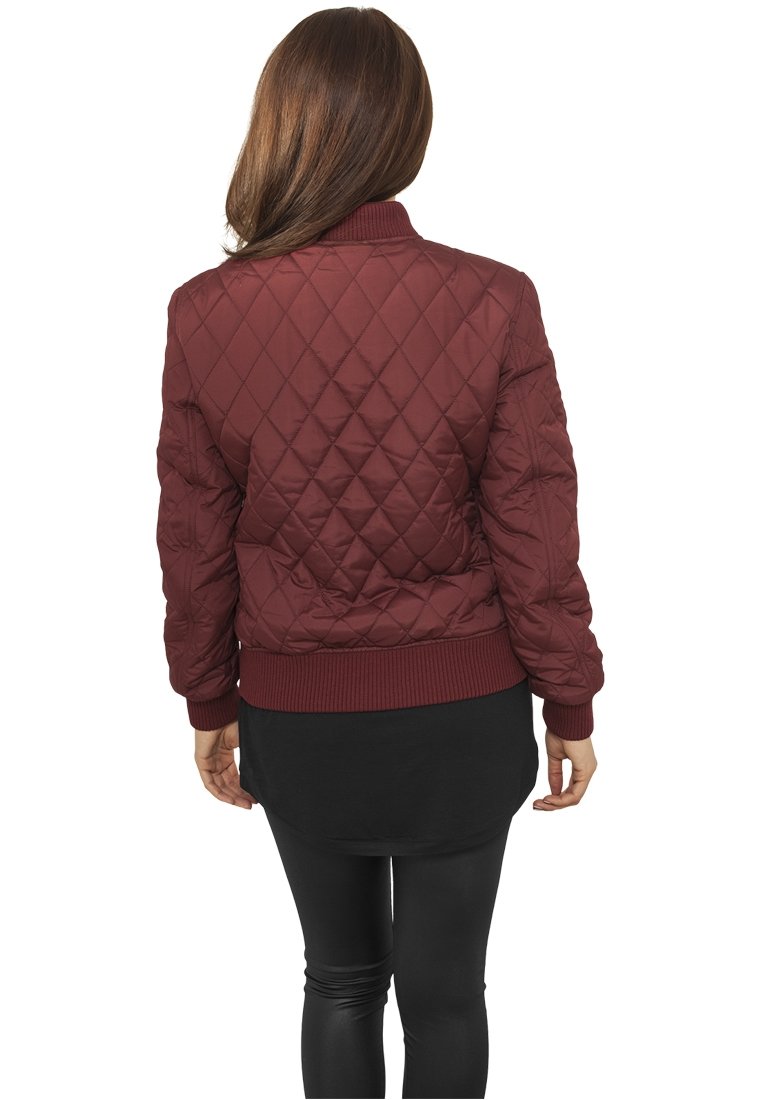 Burgundy quiltad bomberjacka med ribbad mudd och nederkant, med ett diamantmönster och avslappnad passform, sedd bakifrån.