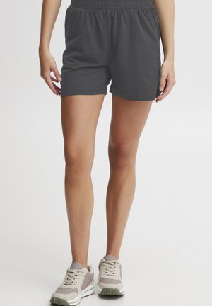 Grå treningsshorts med elastisk midje, kombinert med beige og grå sneakers, med subtile teksturer og en uformell passform.