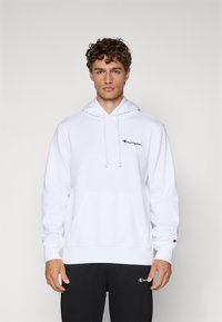 White hoodie with a front pocket, adjustable drawstrings, and a small black "Champion" logo on the chest. Fabric appears soft and smooth.
