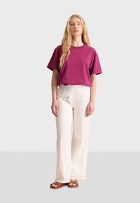 Magenta cotton t-shirt paired with cream textured wide-leg pants featuring patterned details, complemented by brown sandals.