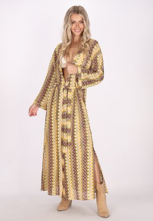Langes, gemustertes Maxikleid in Gelb-, Braun- und Cremetönen; verfügt über lange Ärmel, Knopfdetails und seitliche Schlitze.