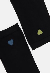 Zwarte sokken met ribbeltextuur, versierd met kleine hartontwerpen: één blauw en één groen. Eenvoudig, functioneel ontwerp met contrasterende accenten.