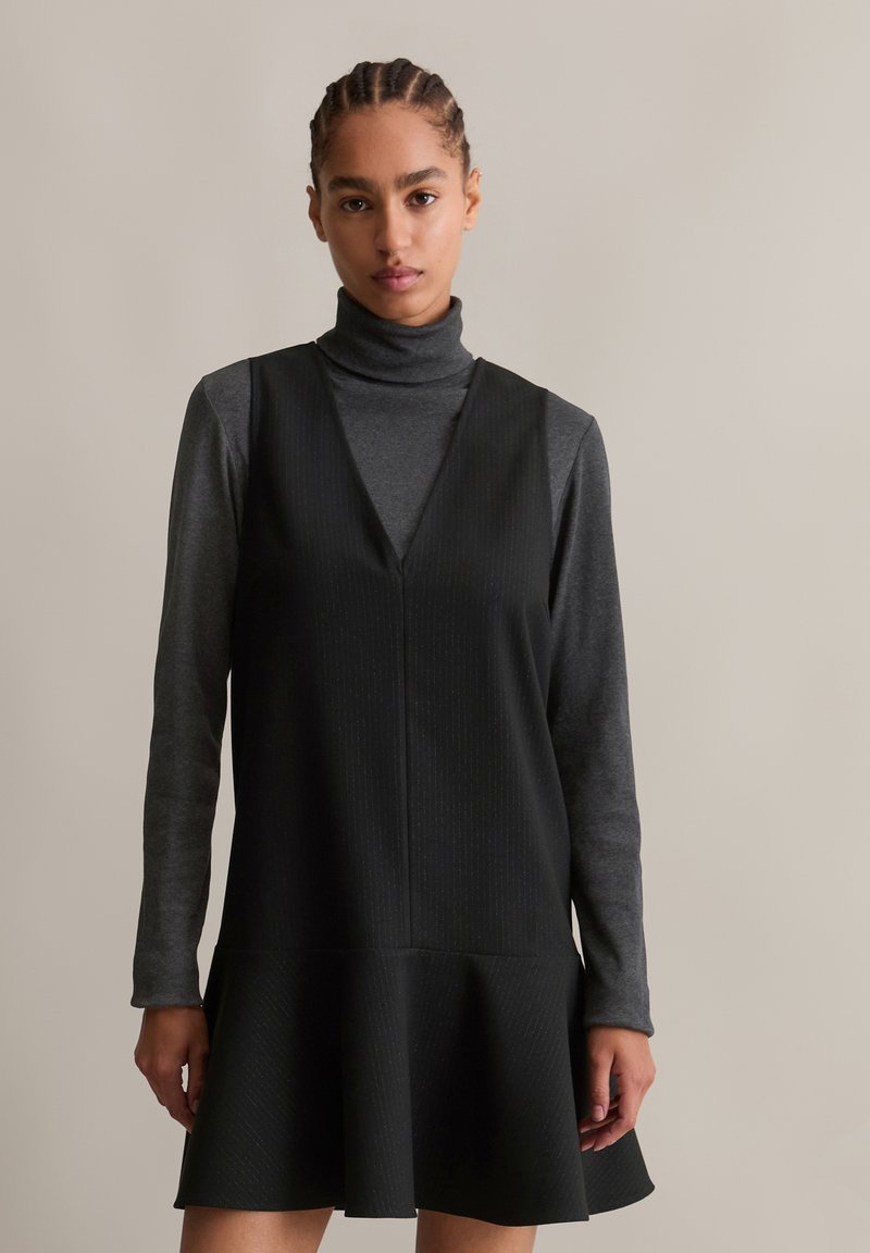 Μαύρο φόρεμα A-line με βαθύ V ντεκολτέ, καλυμμένο με γκρι ψηλό γιακά. Υφή υφάσματος με διακριτές κατακόρυφες ρίγες και ανοιχτή φούστα.