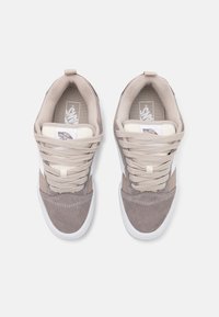 Beige og grå semsket sneakers med lyse snørebånd, polstret krage og hvite detaljer. Har en teksturert ytterside og en merket tunge.