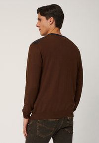 Maglione marrone a maniche lunghe con polsini e bordo a coste, presenta un yoke in maglia blu navy a contrasto sulle spalle, che mette in mostra una texture liscia.