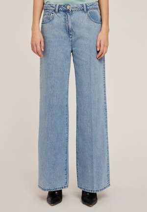 Lichtblauwe wijde spijkerbroek van denim. Voorzien van een knoopsluiting, voorzakken en een ruwe zoom. Soepele textuur met subtiele vervaging.