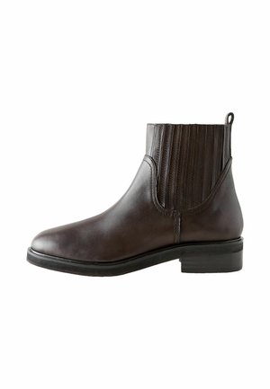 Stivale alla caviglia in pelle marrone con pannelli laterali elastici, punta rotonda e tacco basso a blocco. Presenta un cinturino sul retro per un facile indossamento.