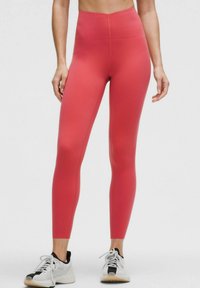 Leggings închise, cu talie înaltă și care se potrivesc pe corp, de culoare corai solidă, realizate dintr-un material elastic. Au o textură netedă, fără modele sau accesorii vizibile.