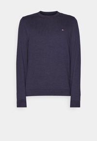 Pull à col rond à manches longues bleu marine avec poignets et ourlet côtelés, arborant un petit logo rouge, blanc et bleu sur le côté gauche de la poitrine.