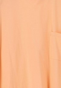 T-shirt en coton pêche à manches courtes, avec un col rond et une seule poche poitrine. Texture lisse, design minimal, sans motifs.