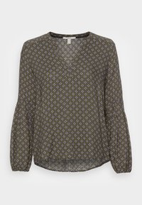 Blouse vert olive avec un col en V, des manches longues bouffantes, et un motif floral en blanc, bleu et violet. Tissu texturé avec une coupe décontractée.