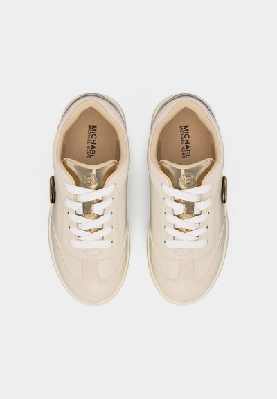 Ζευγάρι μπεζ και χρυσών sneakers Michael Kors με λευκά κορδόνια, λογότυπο στη γλώσσα και αγκράφα στο πλάι, εμφανιζόμενα από πάνω σε λευκό φόντο.