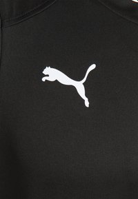 Tissu noir à texture lisse présentant une silhouette du logo Puma en blanc. Le design est minimaliste, mettant l'accent sur la marque.