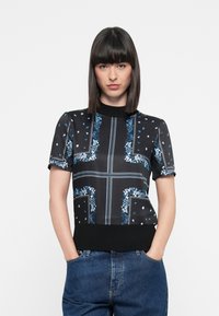 Black short-sleeve top with blue floral patterns, white dots, and contrast ribbed neckline; fitted at the waist and made from smooth fabric.