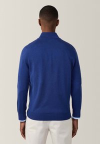 Maglione azzurro a maglia con collo e polsini a coste, caratterizzato da una silhouette dritta e una texture liscia, visto da dietro.
