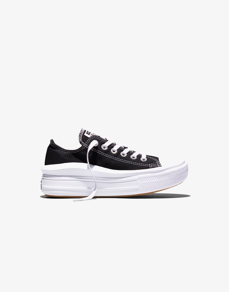 Zwarte lage canvas sneaker met dikke witte zool, witte veters en zichtbare stiksels op een witte achtergrond, zijaanzicht.