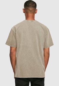 Korte mouwen, ronde hals t-shirt in een gedempt beige kleur. Zachte textuur met een vervaagde afwerking en een standaard pasvorm. Zichtbare stiksels op de mouwen en de zoom.
