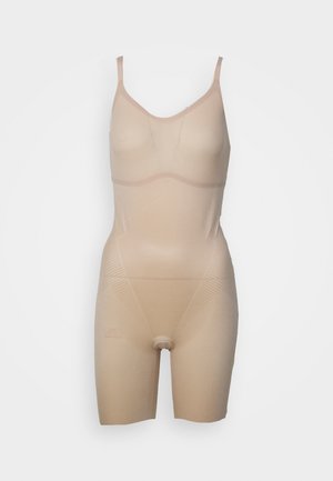 Beige bodysuit met dunne bandjes, naadloos ontwerp en textuur voor het vormen van het lichaam. Materiaal is glad met een lichte glans en heeft een lengte tot midden boven de dijen.