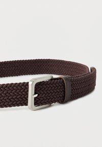 Καφέ υφασμάτινη ζώνη πλεκτή με ασημένια μεταλλική αγκράφα και δερμάτινη θηλιά ζώνης σε λευκό φόντο.