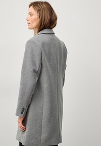 Grijze wollen jas met een op maat gemaakte ontwerp, lange mouwen en gekartelde revers. Inclusief knoopaccenten op de manchetten en een gestroomlijnd silhouet.