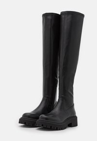 Svarta knähöga stövlar i slät läder, med dragkedja på sidan, tjock sula och räfflad mönstring för bra grepp.