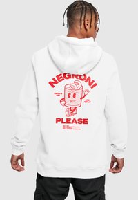 Hvit hettegenser med et rødt grafisk design på baksiden som viser en tegneserie-drikkefigur og tekst: "Negroni, vær så snill" samt oppskrift detaljer.