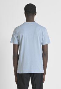 Camiseta de algodón de color azul claro con mangas cortas y un escote redondo, que presenta una textura suave y un diseño limpio y sencillo en la parte trasera.