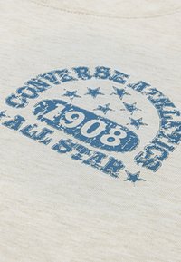 Béžová bavlnená mikina s modrým opotrebovaným tlačovým vzorom: "CONVERSE ATHLETIC 1908 ALL STAR" s okolitými hviezdami a kruhovým dizajnom.