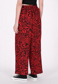 Rode en zwarte geblokte brede broek van textuurstof, met een elastische tailleband en gecombineerd met zwarte sneakers.