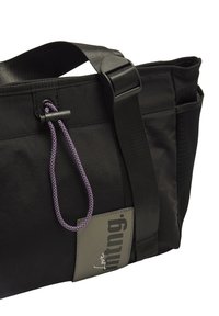 Sac en tissu noir avec une surface texturée, doté d'un cordon de serrage violet, d'une sangle noire et d'un patch de marque gris. Comprend une poche latérale en mesh.