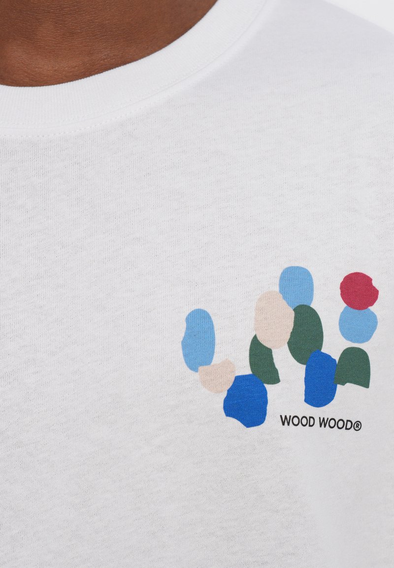 Short-sleeve white cotton t-shirt featuring abstract colored shapes in blue, green, beige, and red, with 'WOOD WOOD®' printed below.