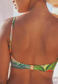 Šareni bikini top s tropskim uzorcima lišća, podesivim trakama i metalnim kopčanjem na leđima.