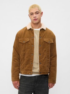 Brun køyrepelsjakke med en beige faux shearling krage, front knappelukking og to brystlommer; brukt over en lys beige genser.