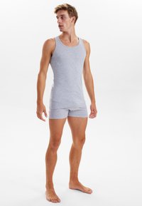 Grå bomulds tanktop og matchende shorts, med en tætsiddende pasform og glat tekstur, uden mønstre eller accenter. Bæres af en stående model.